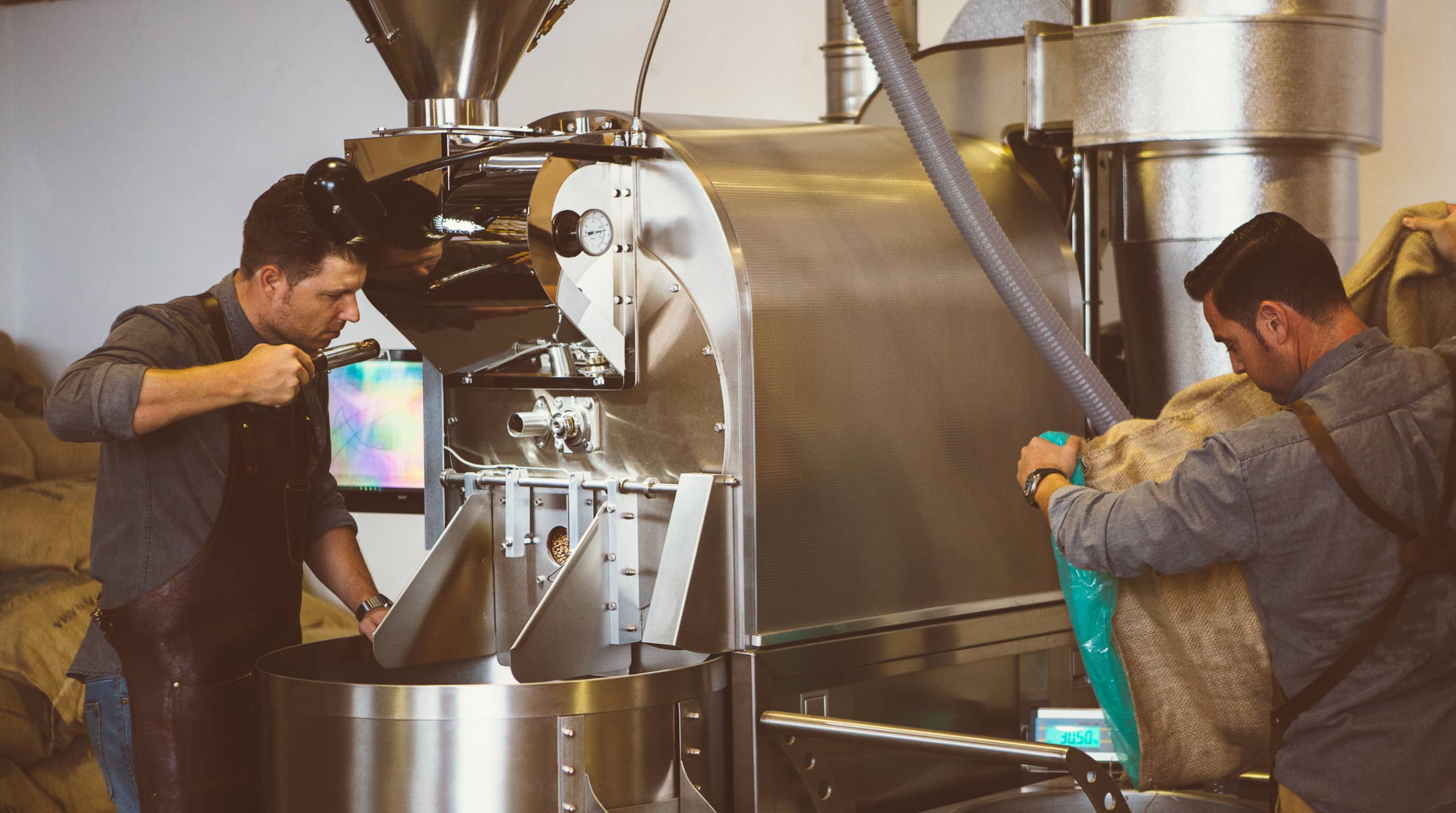 Two men roasting coffee in a Loring roaster