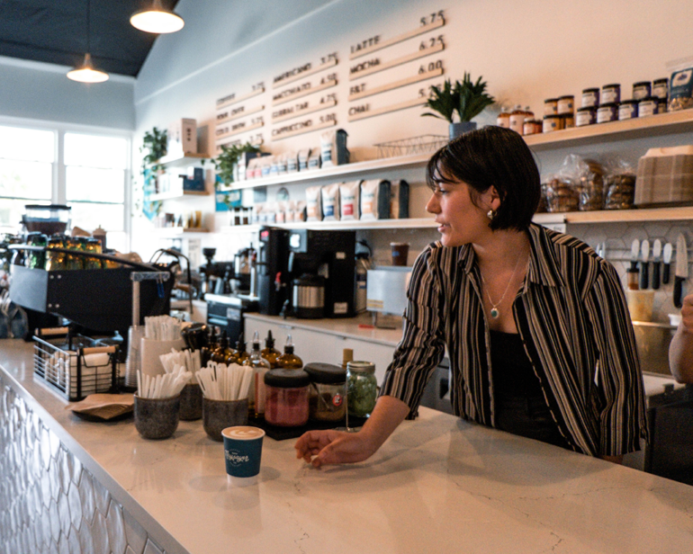 A female barista places a latte on the counter of Naysayer's flagship coffee shop in a residential area of Napa.