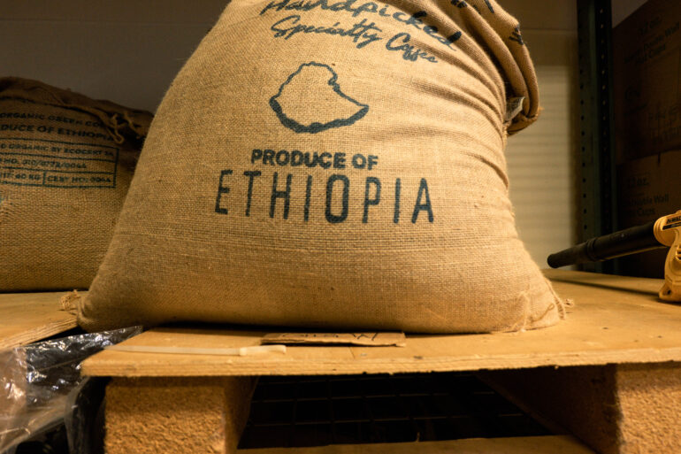 A burlap bag of Ethiopian specialty coffee sitting on a wooden shelf at the roastery.
