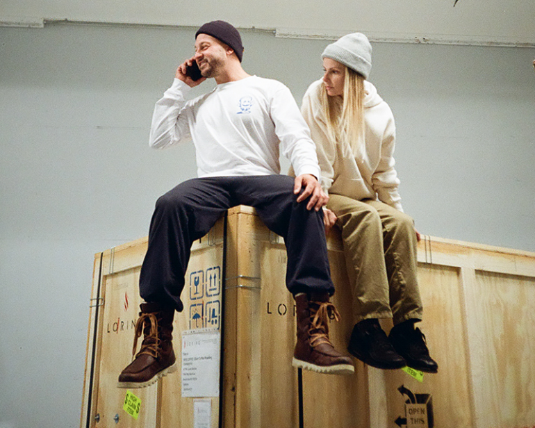 John Pierce and Lauren Webster sitting on top of a crate containing a Loring S15 roaster.