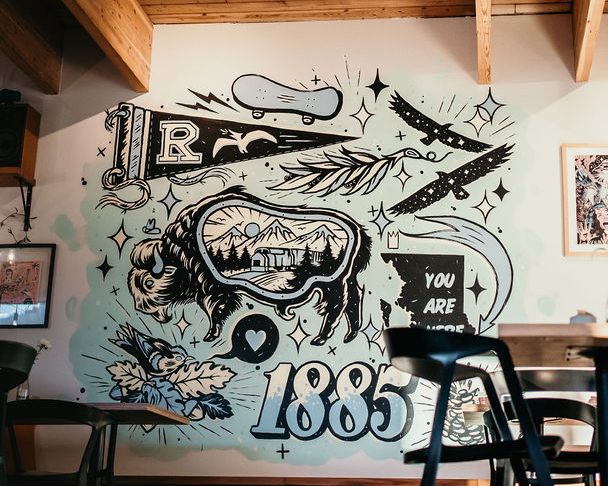 A mural on the wall of Dose cafe depicting elements of Revelstoke history and culture, including a train and the founding year.
