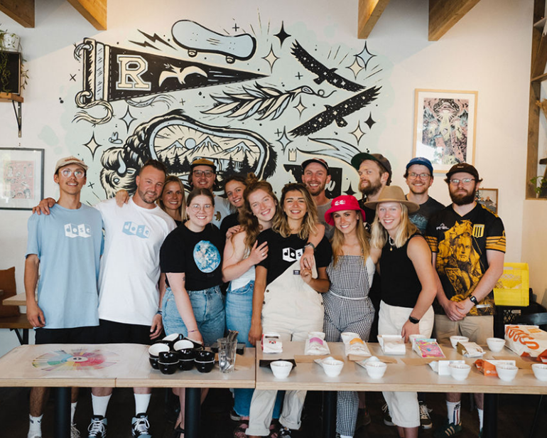 A group photo of the Dose Coffee team  in front of the cafe's mural.