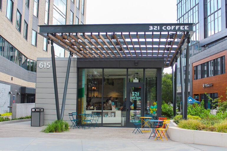 An outside view of a 321 Coffee café featuring their glass front doors and a dark awning overhead